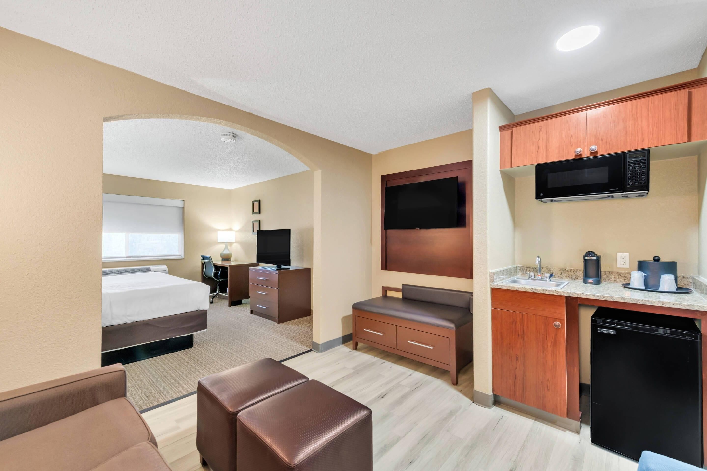 A hotel room with a bed, a desk, a TV, a microwave, and a coffee maker.