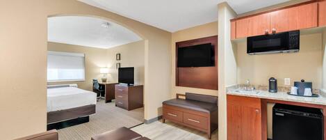 A hotel room with a bed, a desk, a TV, a microwave, and a coffee maker.