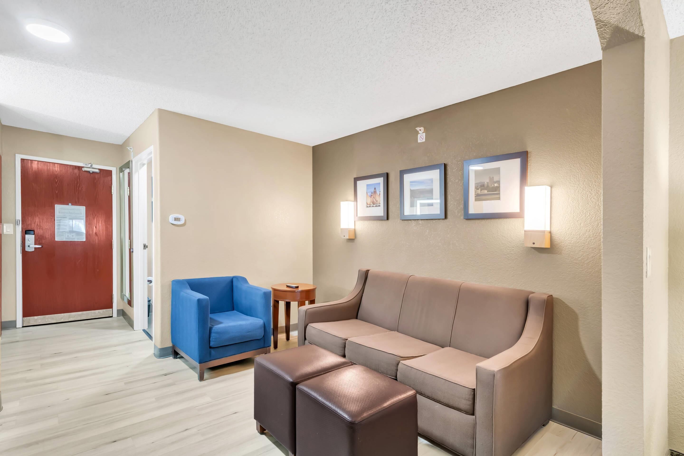 A hotel lobby with a brown sofa, a blue armchair, and a small table.