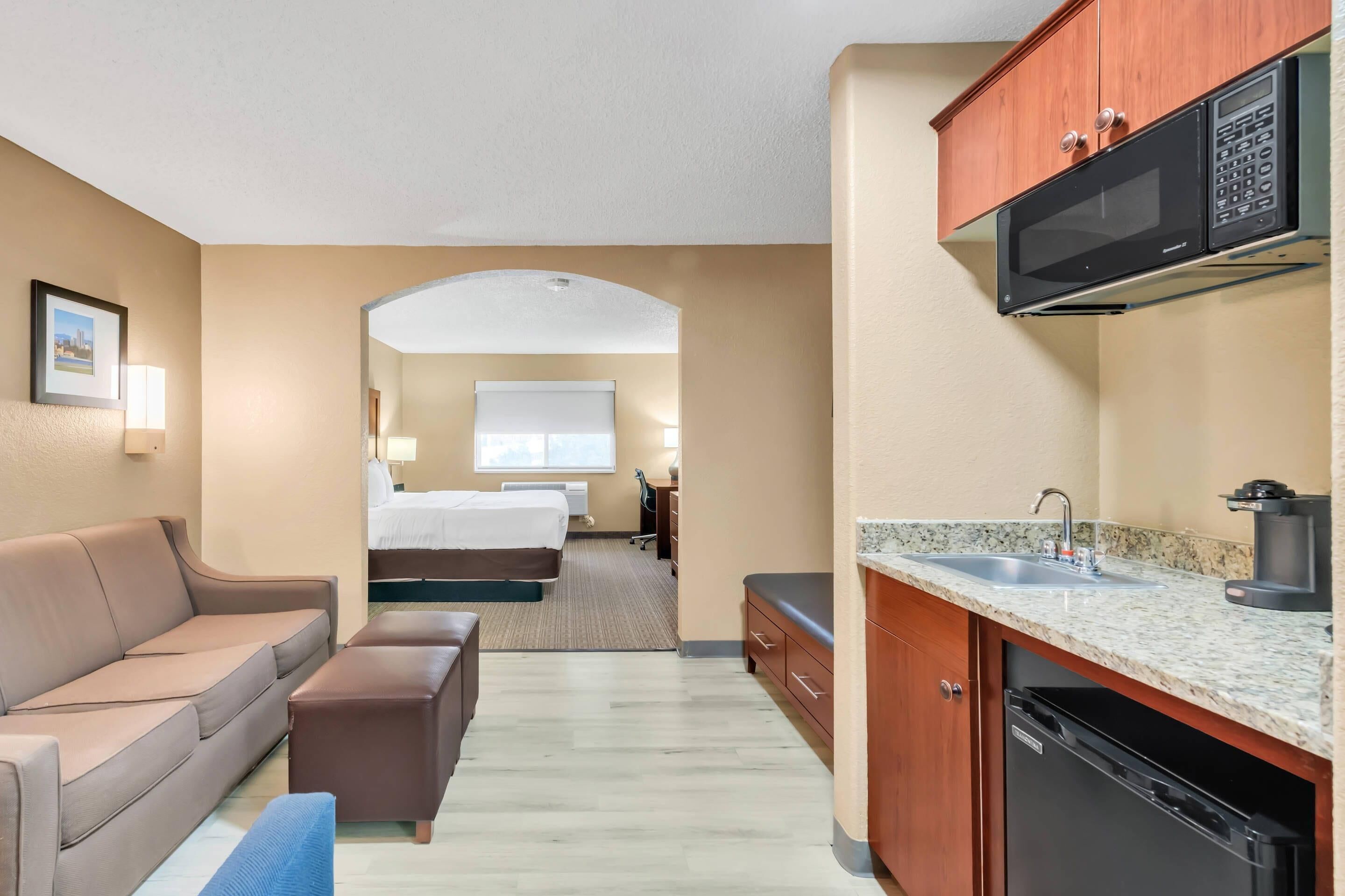 Habitación de hotel compacta con kitchenette, una cama, un sofá y un pequeño comedor.
