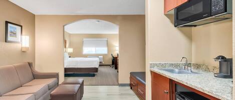 Habitación de hotel compacta con kitchenette, una cama, un sofá y un pequeño comedor.