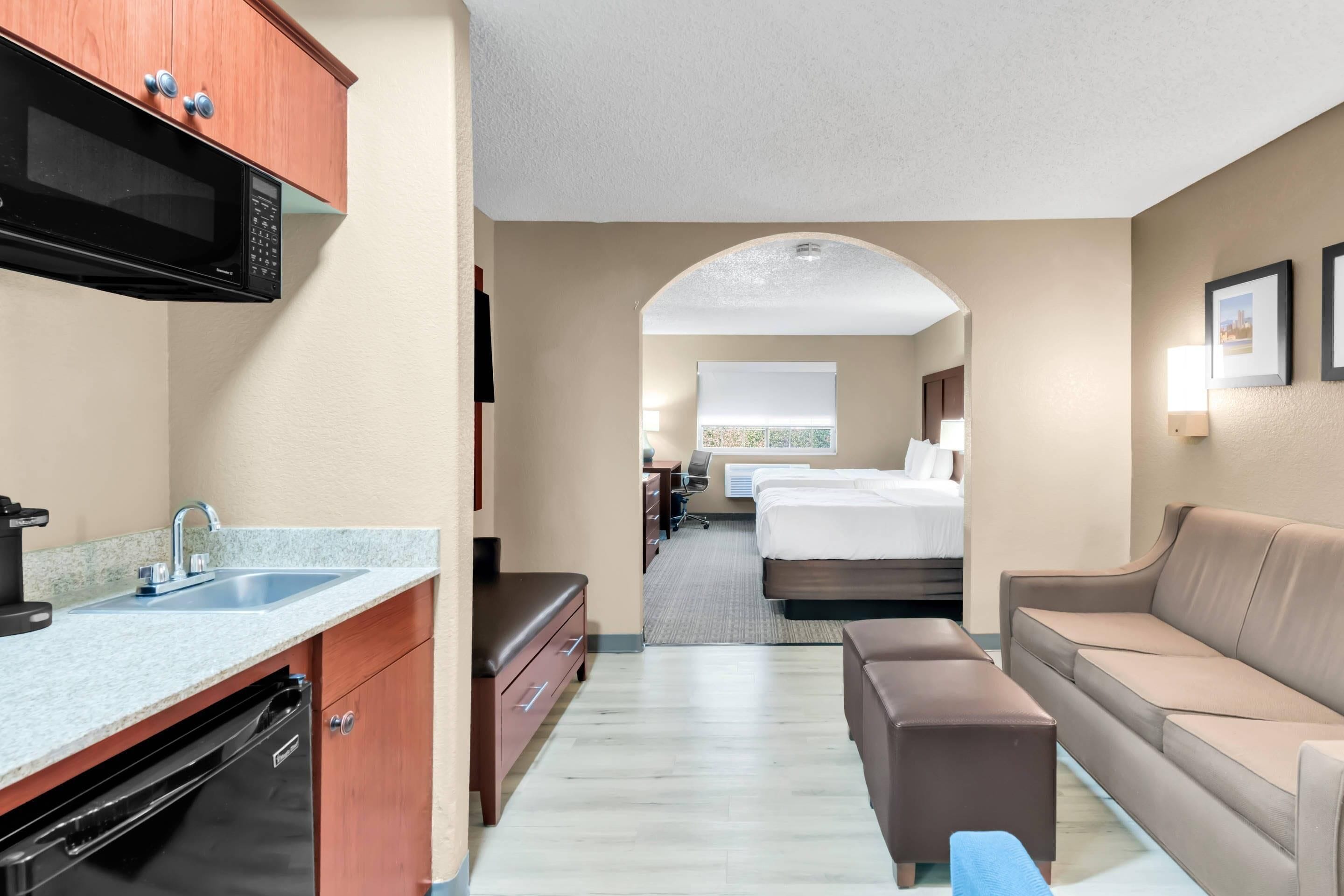 Une chambre d’hôtel équipée d’une kitchenette, d’un lit, d’un canapé et d’une salle de bain.