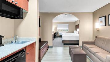 Une chambre d’hôtel équipée d’une kitchenette, d’un lit, d’un canapé et d’une salle de bain.