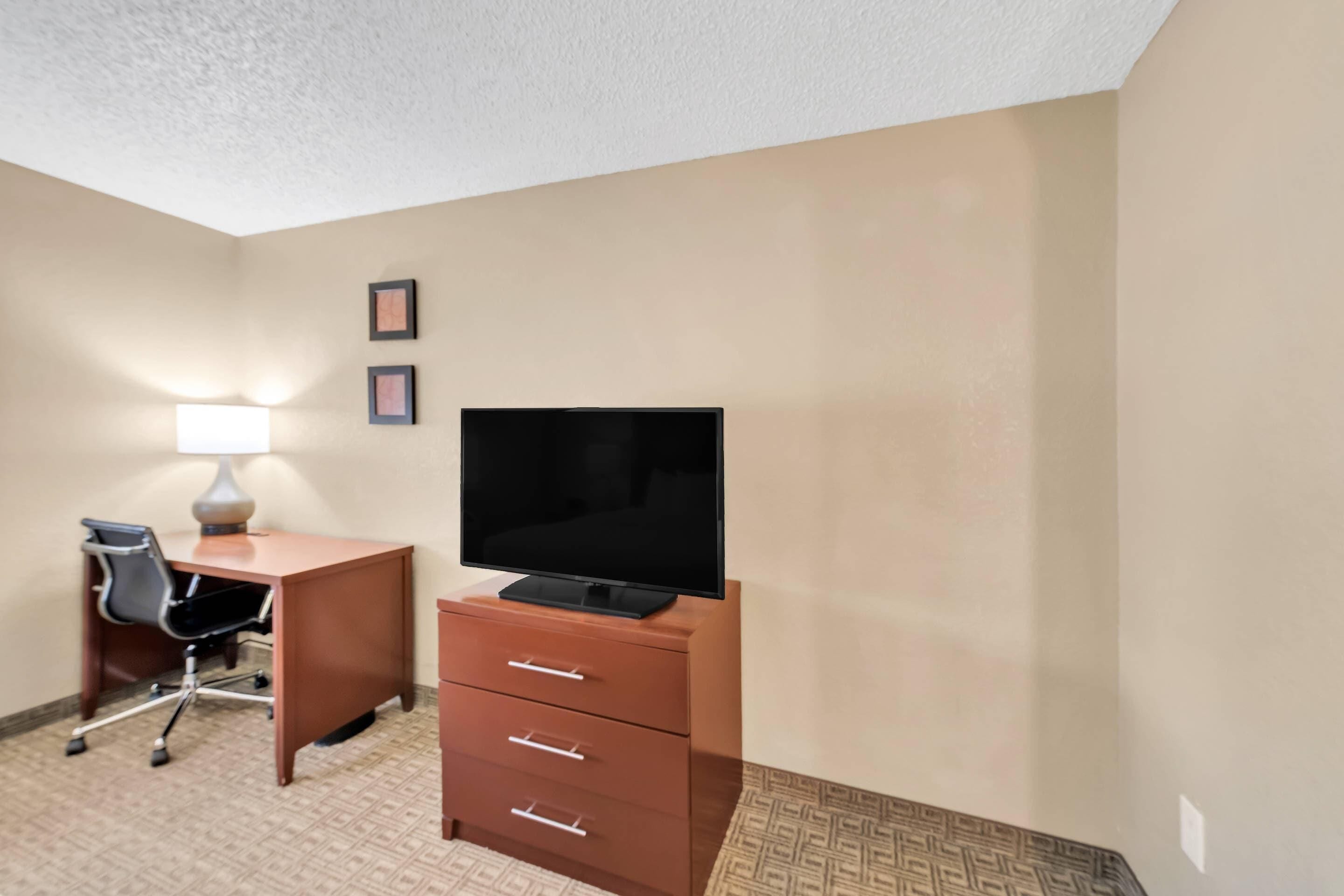 Ein Hotelzimmer mit Schreibtisch, Stuhl, Fernseher und Lampe.