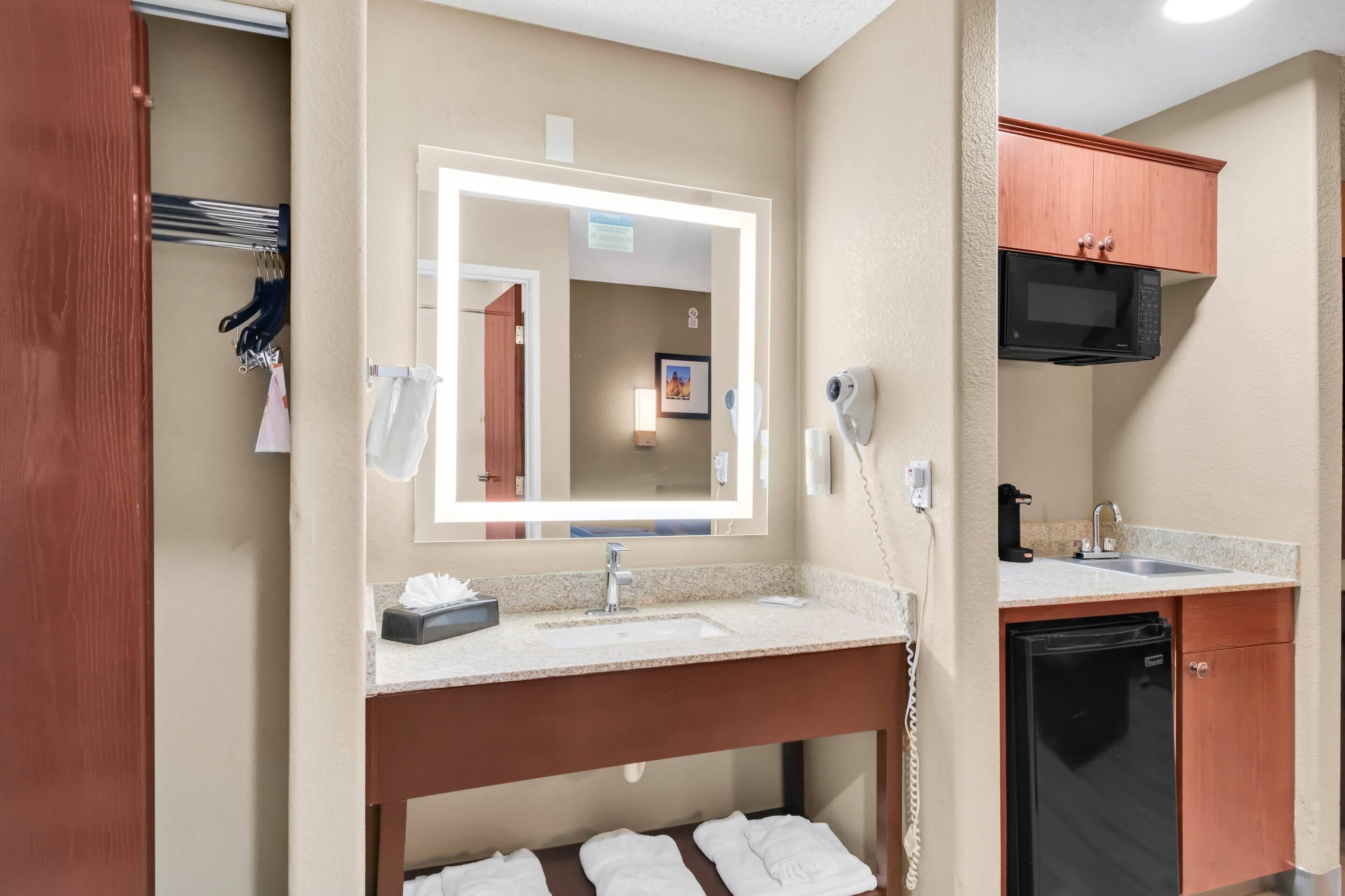 Ein Hotelbad mit Waschbecken, Spiegel, Handtuchhalter und einer Mikrowelle über dem Waschbecken.