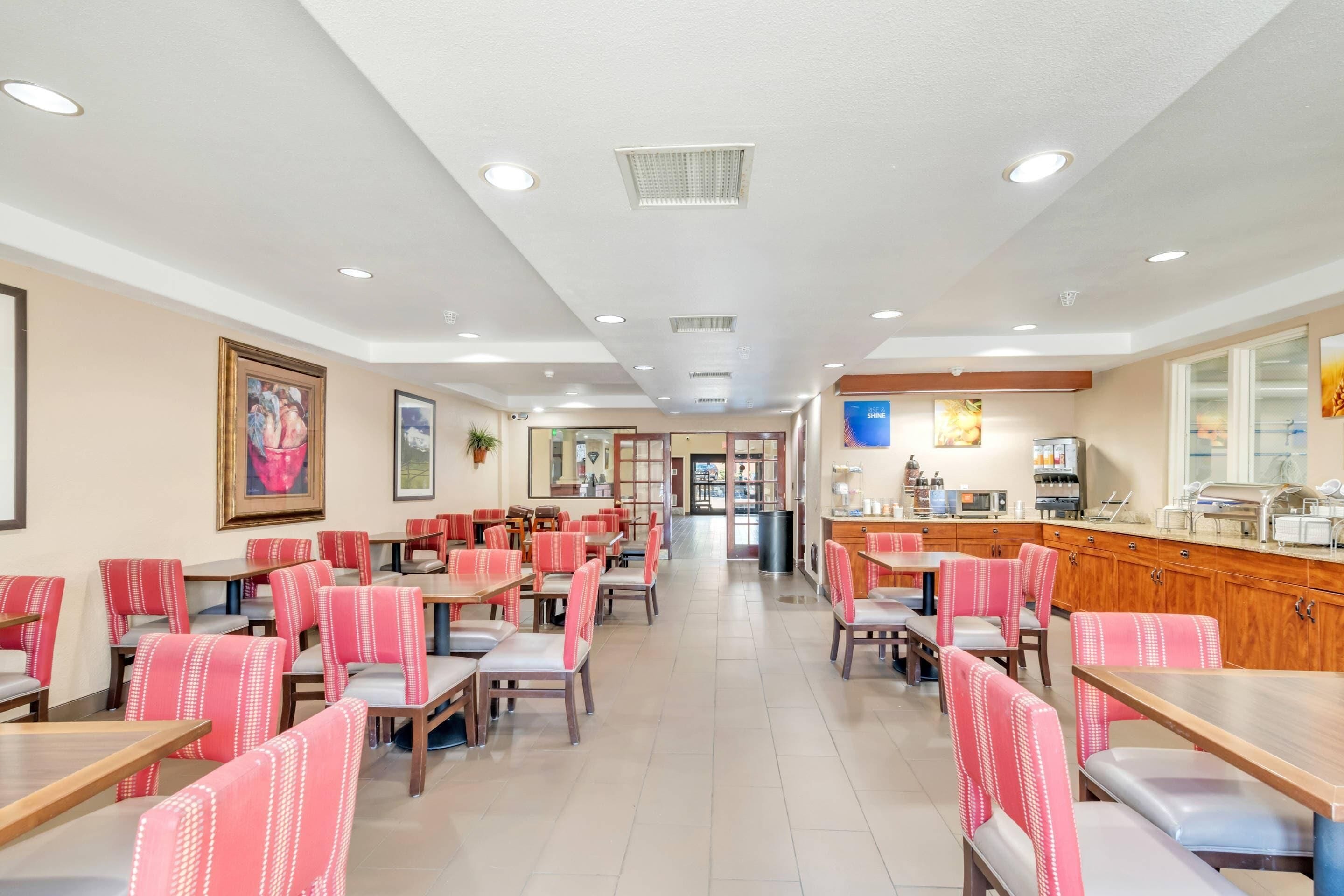A spacious restaurant with multiple tables and chairs, a counter with a menu, and framed artwork on the walls.