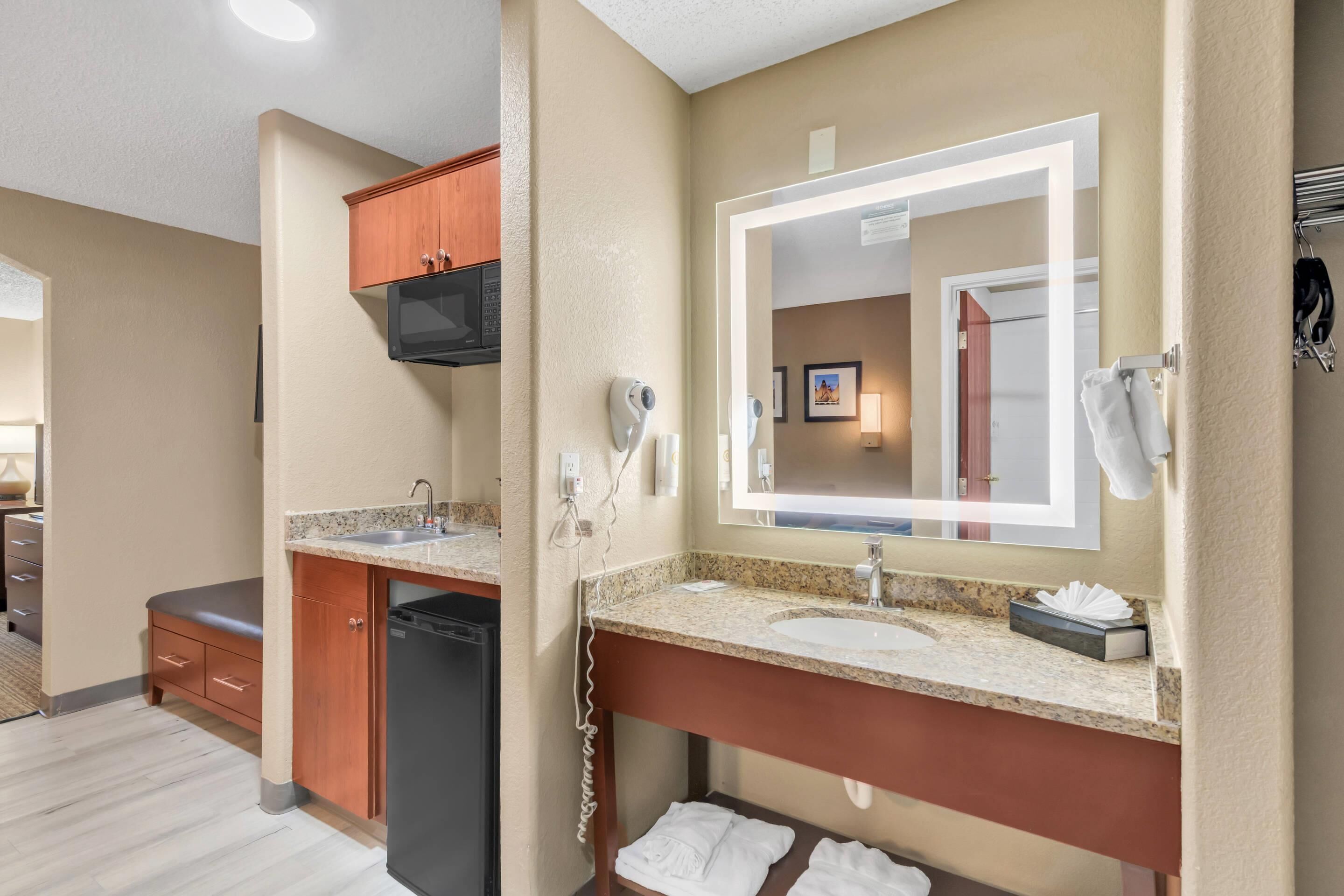 A modern bathroom with a granite countertop sink, a large mirror, and a built-in hairdryer.