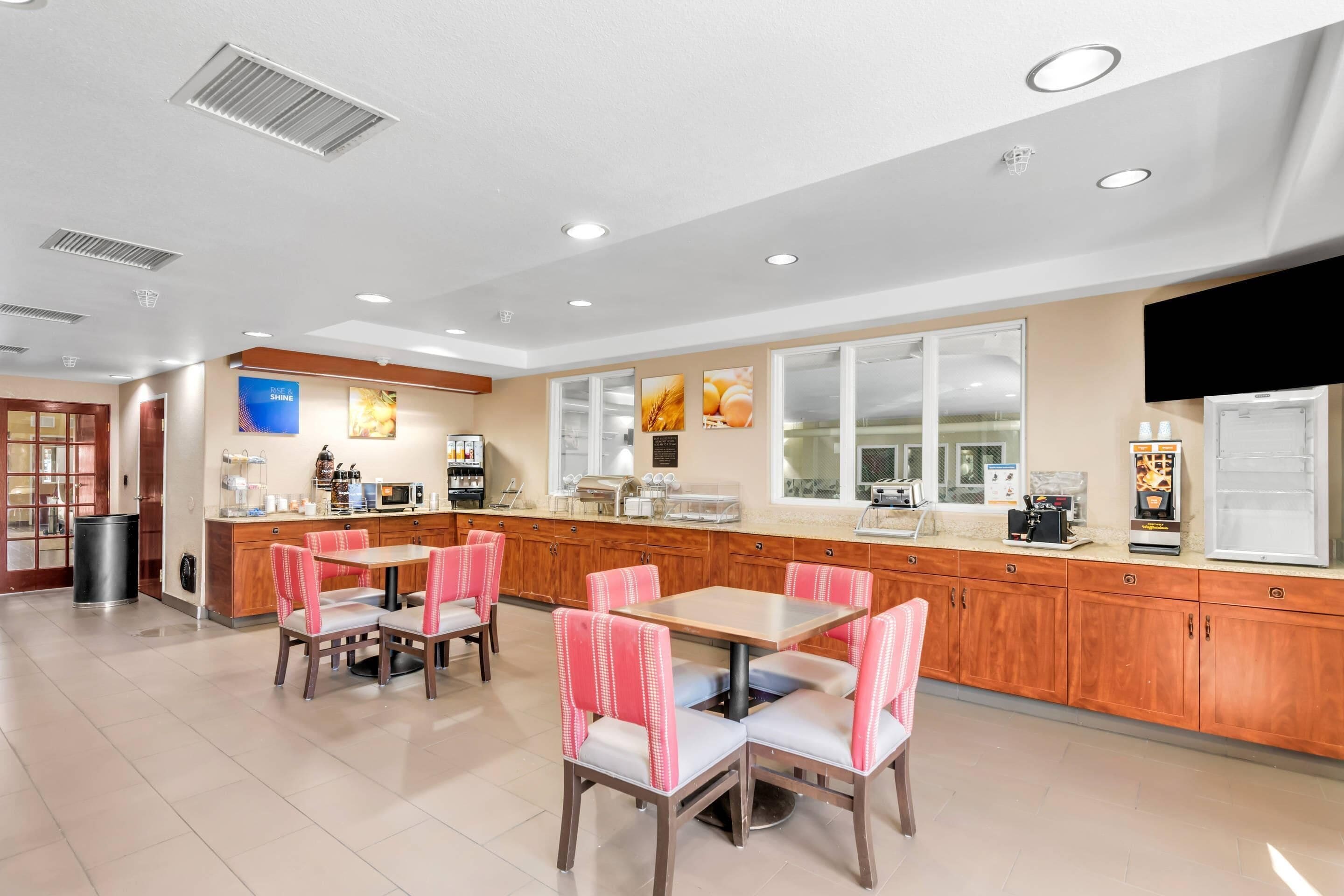 A modern kitchen with wooden cabinets, a central island, and a seating area with chairs.