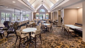 A hotel lobby with multiple seating areas, including round tables and chairs, and a patterned carpet. - Residence Inn by Marriott Denver Southwest/Lakewood (Lakewood)