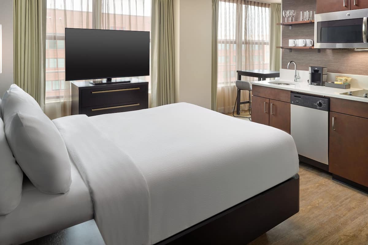 Une chambre d’hôtel avec un lit, une télévision, une kitchenette et une vue sur la ville.