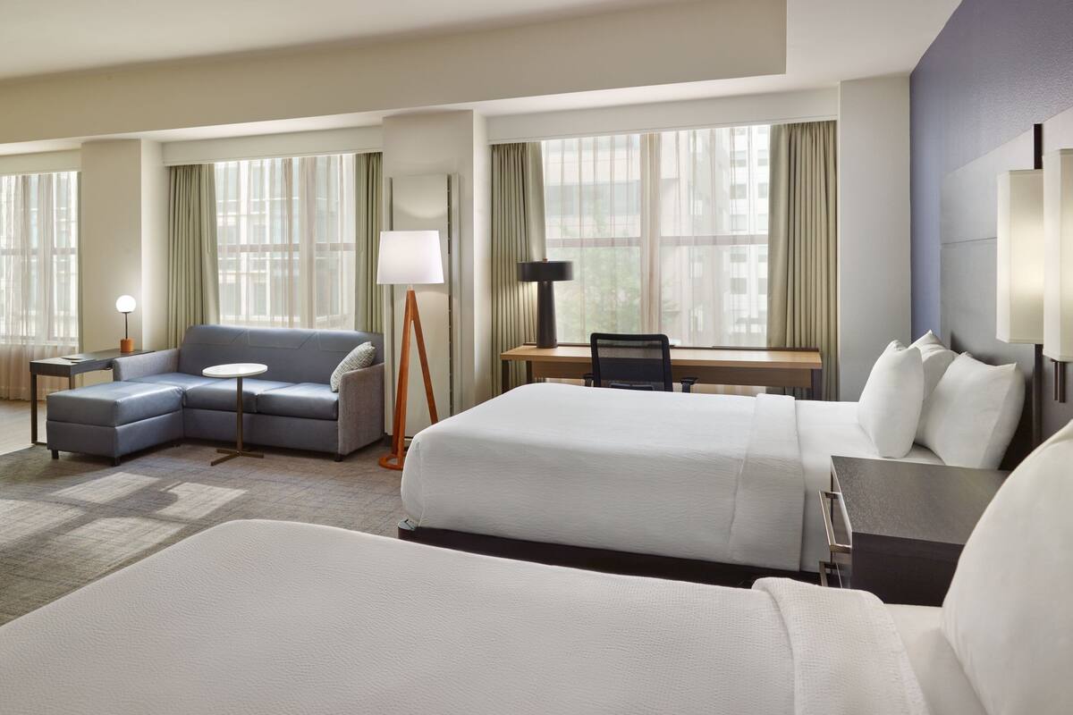 Une chambre d’hôtel avec un grand lit, un canapé, un bureau et une chaise.
