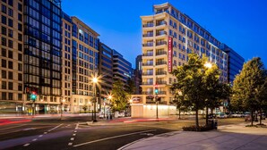 Hotel modern amb diverses plantes, un senyal vermell destacat i un carrer ben il·luminat.