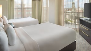 Habitació d'hotel amb dos llits, televisió i un balcó amb vista a la ciutat.