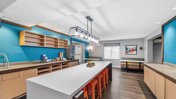 A modern kitchen with a central island, wooden cabinets, and a blue accent wall.