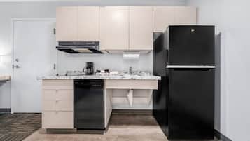 Una cocina moderna con armarios de madera clara, un refrigerador negro, lavavajillas integrado y encimera de mármol.