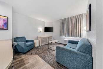 A modern kitchen with white cabinets, a black refrigerator, a microwave, and a granite countertop. at MainStay Suites Orlando Altamonte Springs
