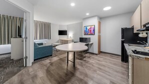 A modern kitchen with a dining area, a TV, and a sofa.