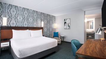 Habitación de hotel con una cama grande, un escritorio, una silla, una mesita de noche y un papel tapiz con diseño.