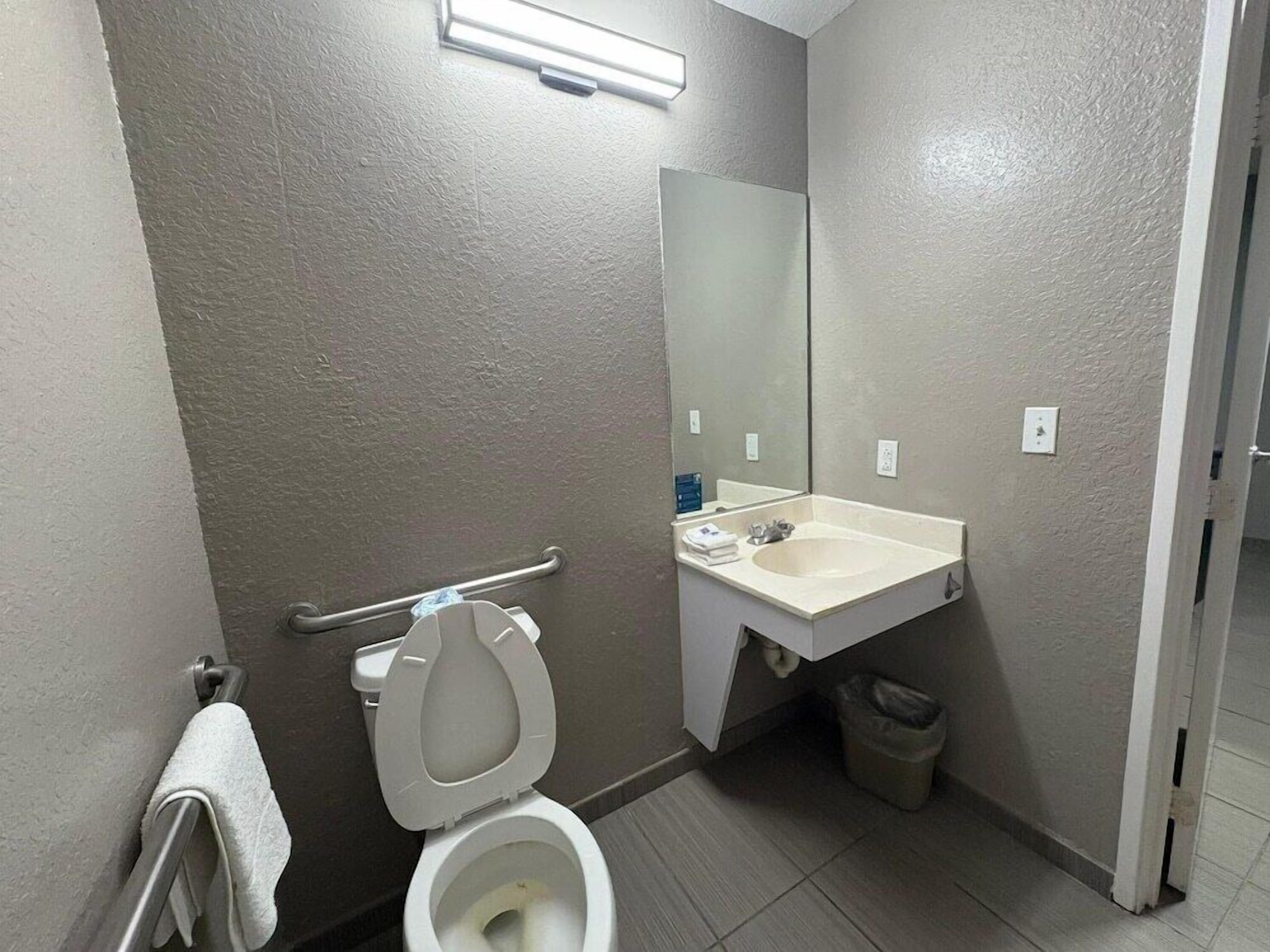 A small, clean bathroom with a toilet, sink, and mirror.