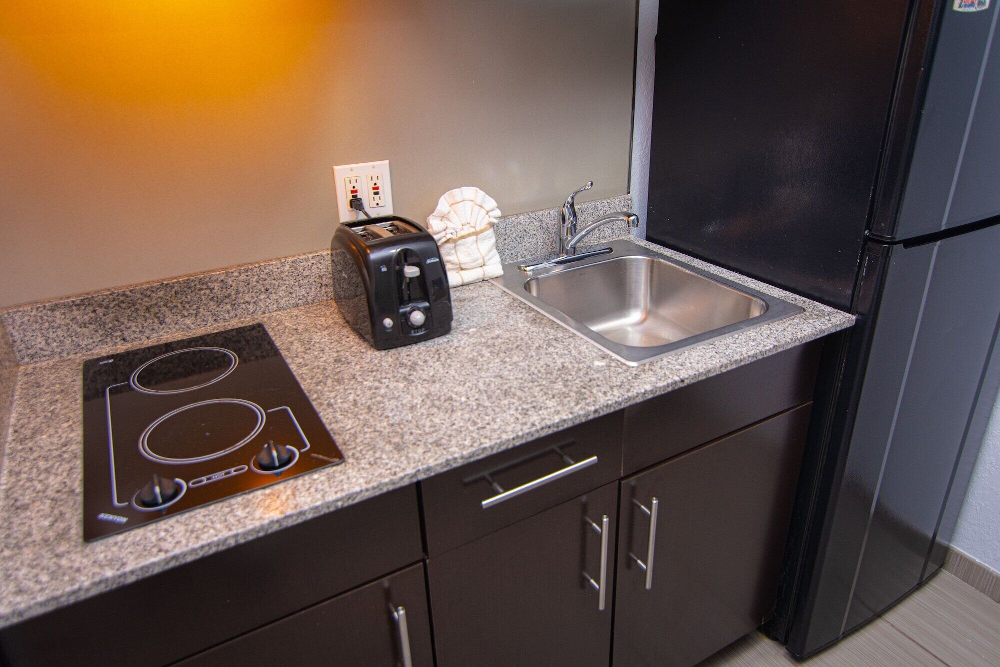 Una kitchenette equipada con un tostador, una tetera, un lavabo y una estufa.