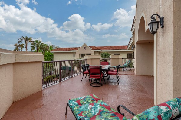A covered outdoor patio with a table and chairs, a lounge chair, and a railing. - Best Western Gateway Grand (Gainesville)