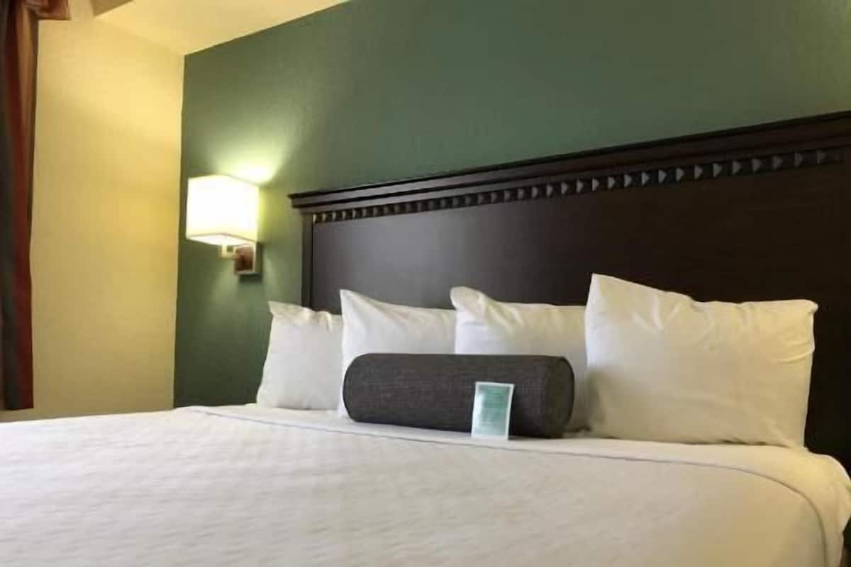 A neatly made bed with white bedding and a dark headboard.