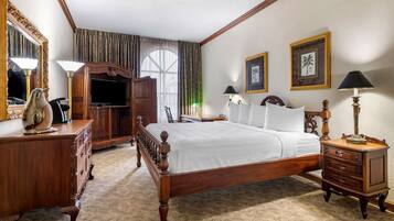 A hotel room with a wooden bed, a dresser, a TV, and a large mirror.