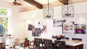 A dining area with a long table, multiple chairs, and hanging pendant lights.