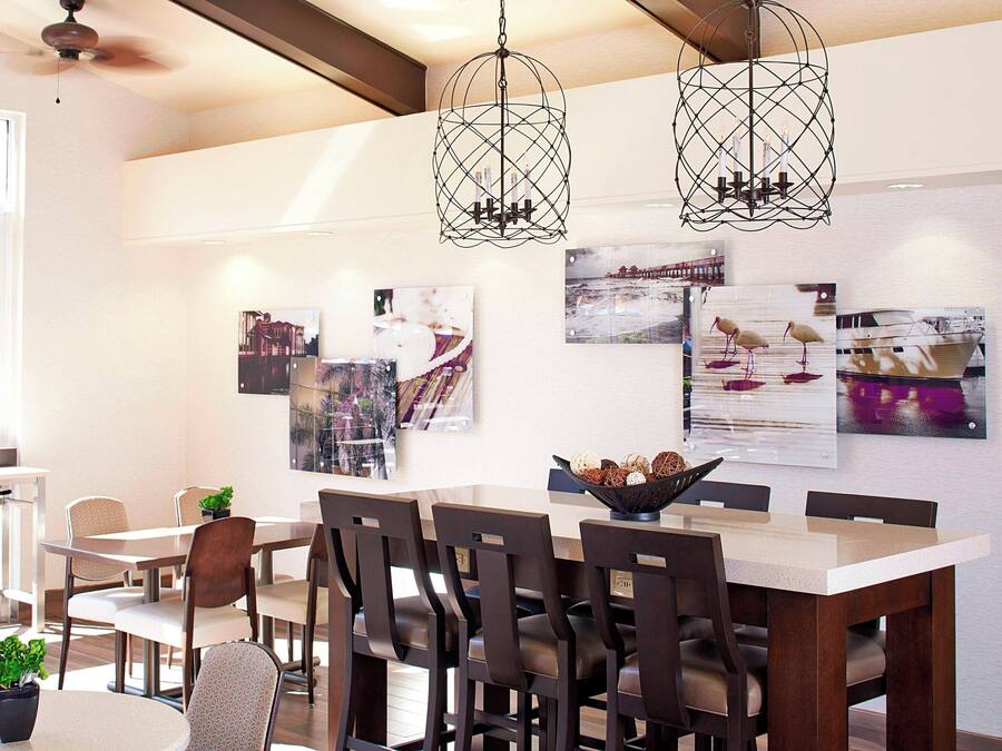 A dining area with a long table, multiple chairs, and hanging pendant lights.