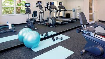 Un gimnasio con cintas de correr, elípticas y pelotas de ejercicios.