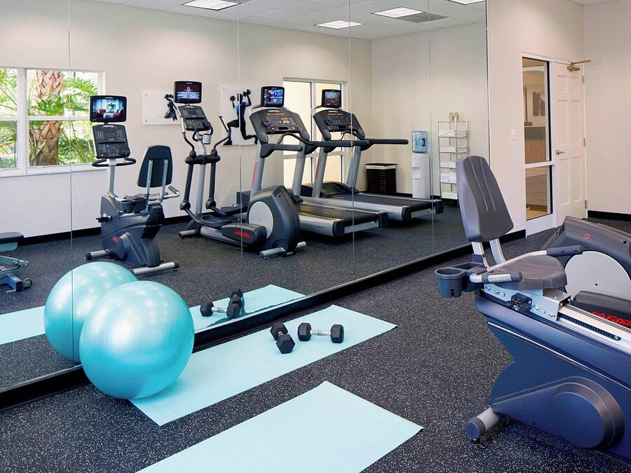 Un gimnasio con cintas de correr, elípticas y pelotas de ejercicios.