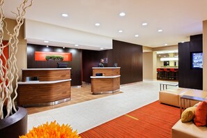 Welcome to our hotel lobby, featuring a reception desk and comfortable seating area with a sofa and chair.