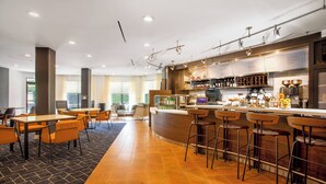 Eine moderne Hotelhalle mit Barbereich, Sitzgelegenheiten und einer Rezeption.