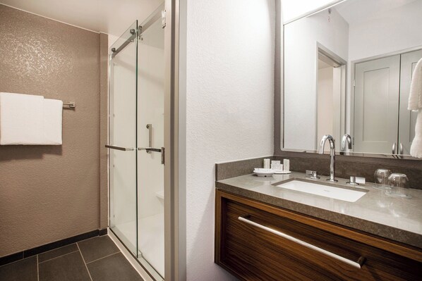 A modern bathroom with a glass shower enclosure, a wooden vanity with a sink, and a large mirror.