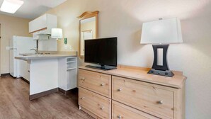 A compact kitchen with a refrigerator, stove, sink, and a TV on a wooden cabinet. - Extended Stay America Select Suites Orlando Southpark (Orlando)