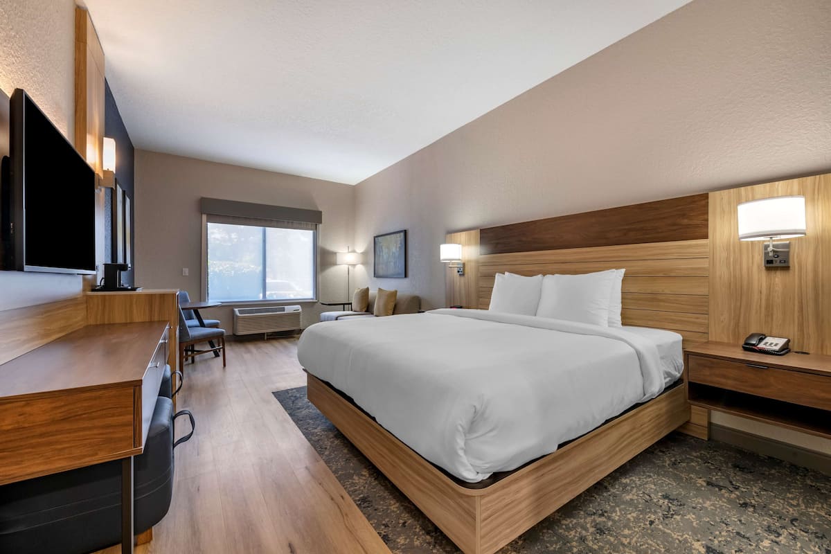 A modern hotel room with a large bed, a desk, and a television.
