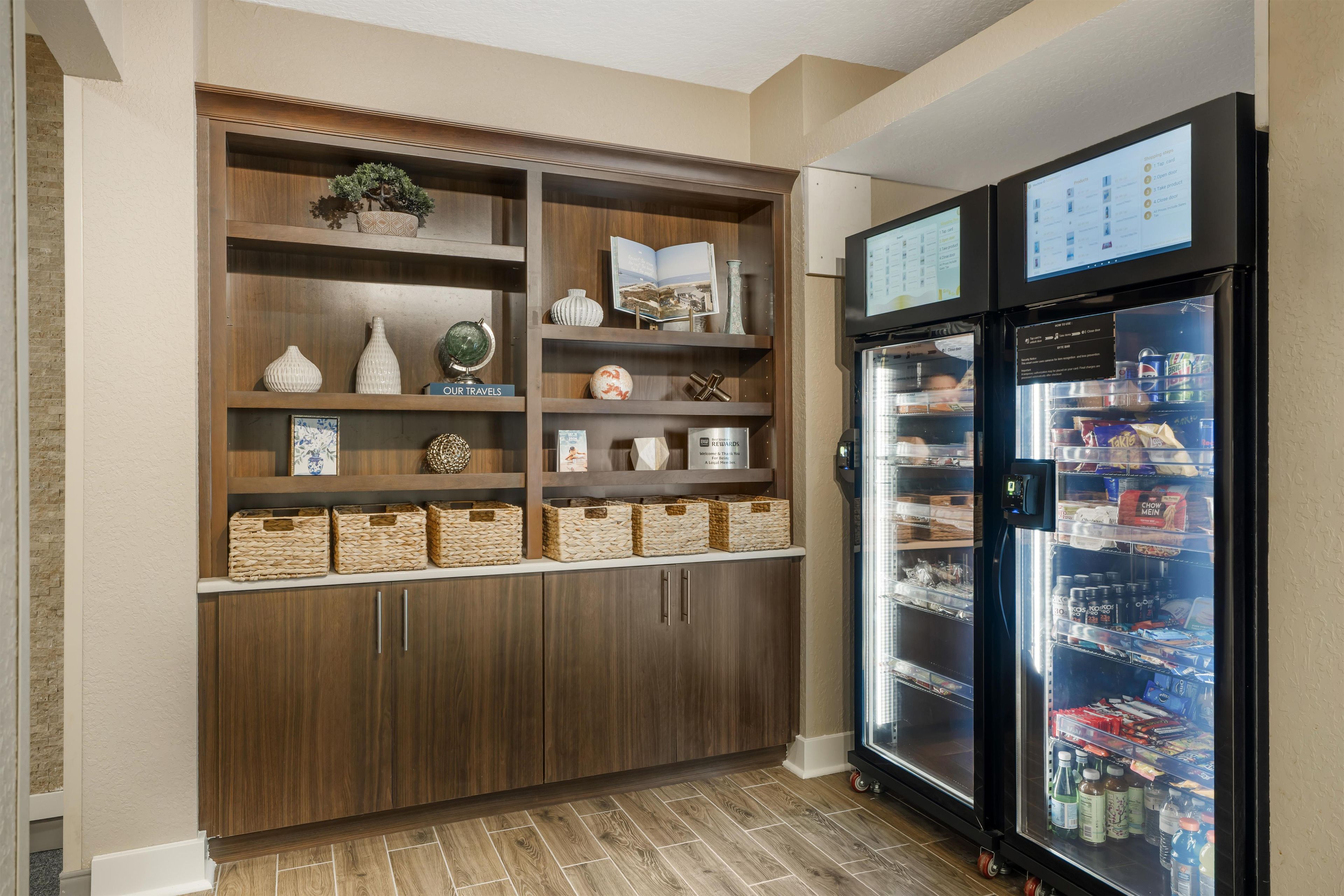 A kitchenette with a built-in refrigerator stocked with beverages and snacks, wooden cabinets with decorative items, and a small globe.