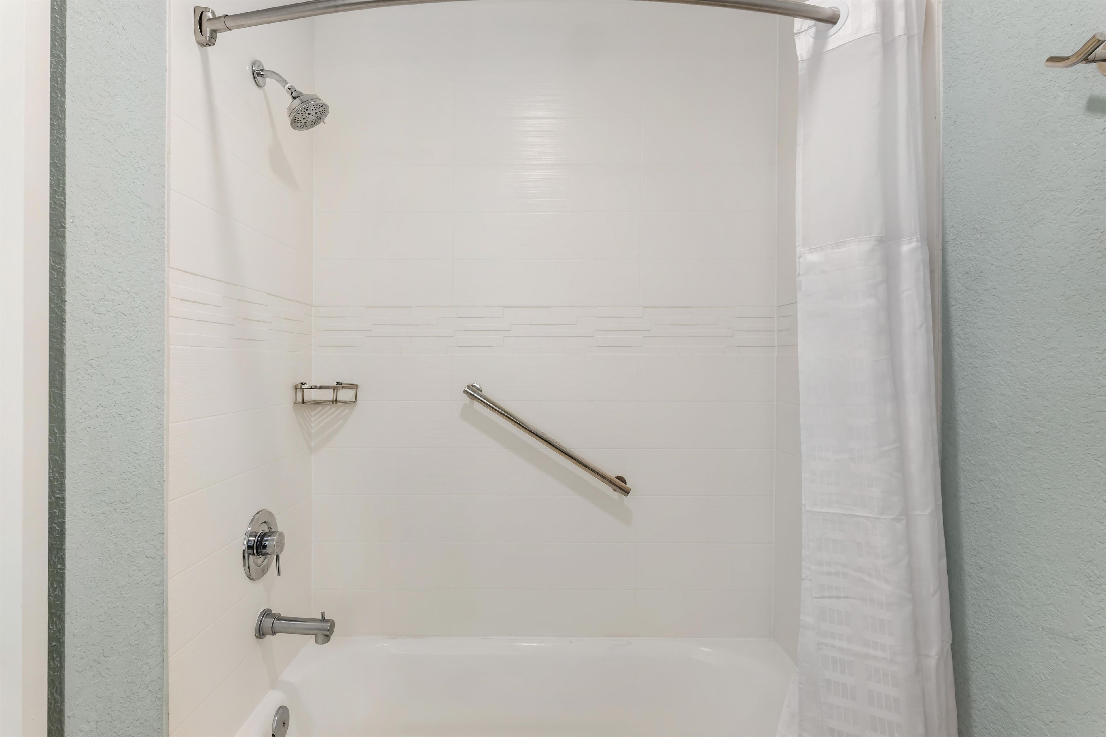 A shower with a handheld showerhead, a handheld shower bar, and a wall-mounted faucet.