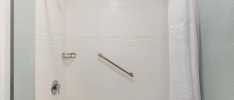 A shower with a handheld showerhead, a handheld shower bar, and a wall-mounted faucet.