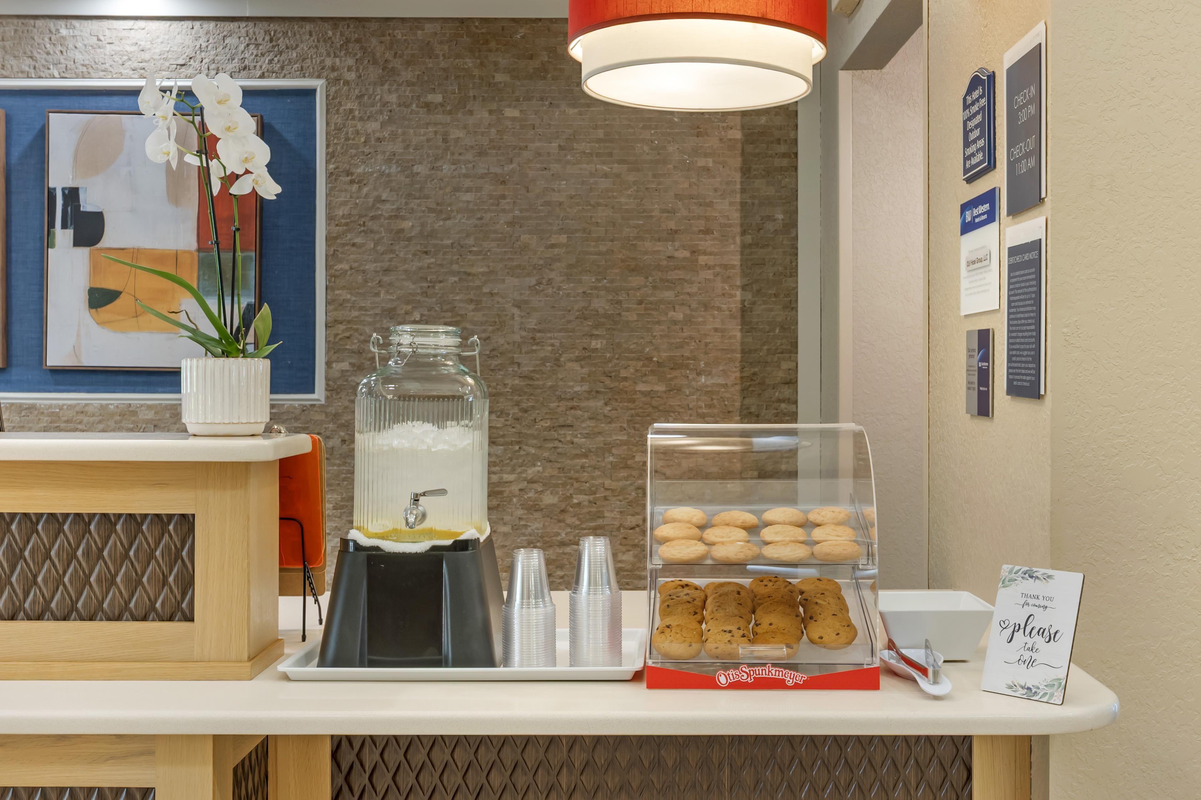 A breakfast bar with a coffee dispenser, a glass jar, and a display of cookies.