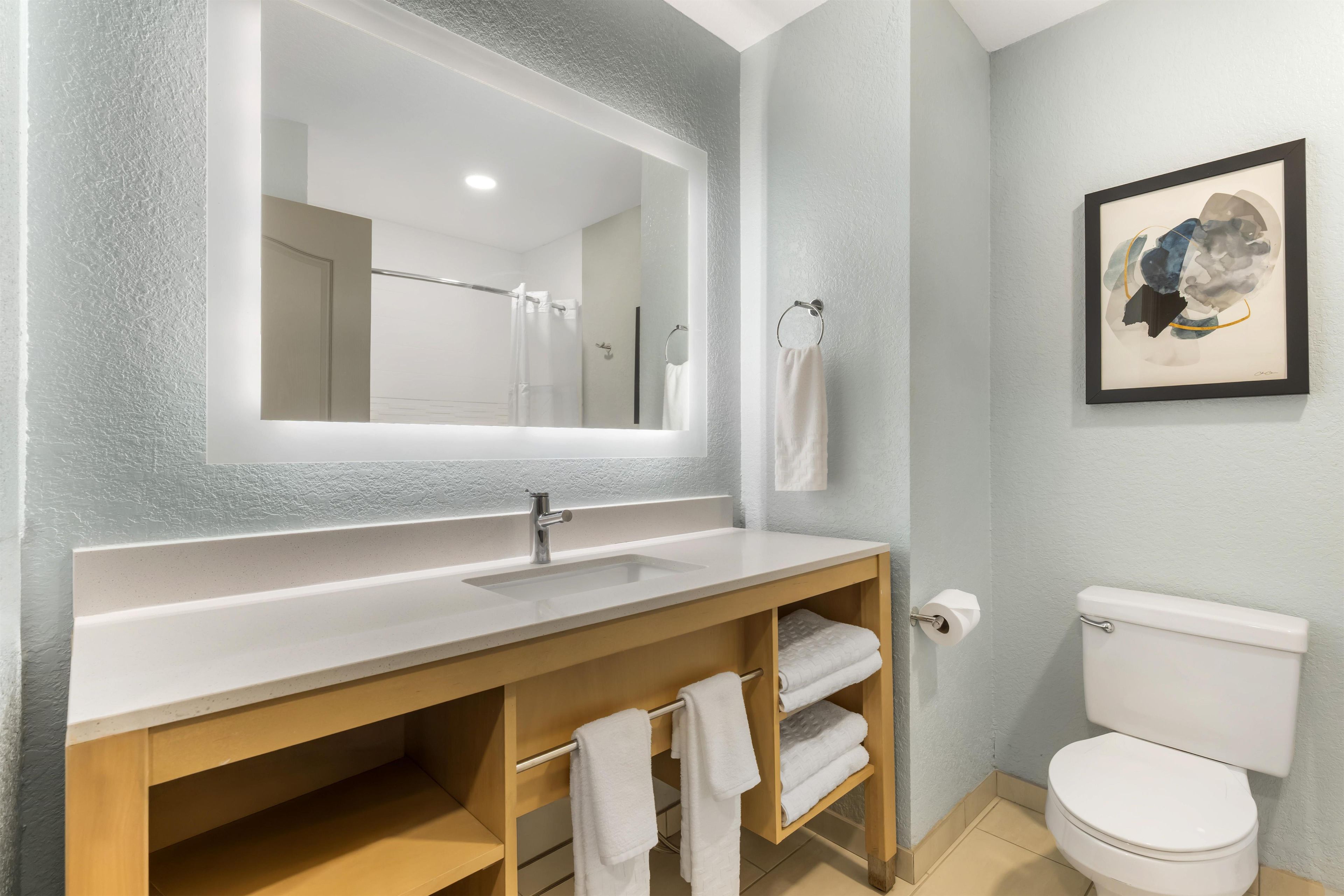 A bathroom with a white sink, a mirror, a toilet, and a towel rack.