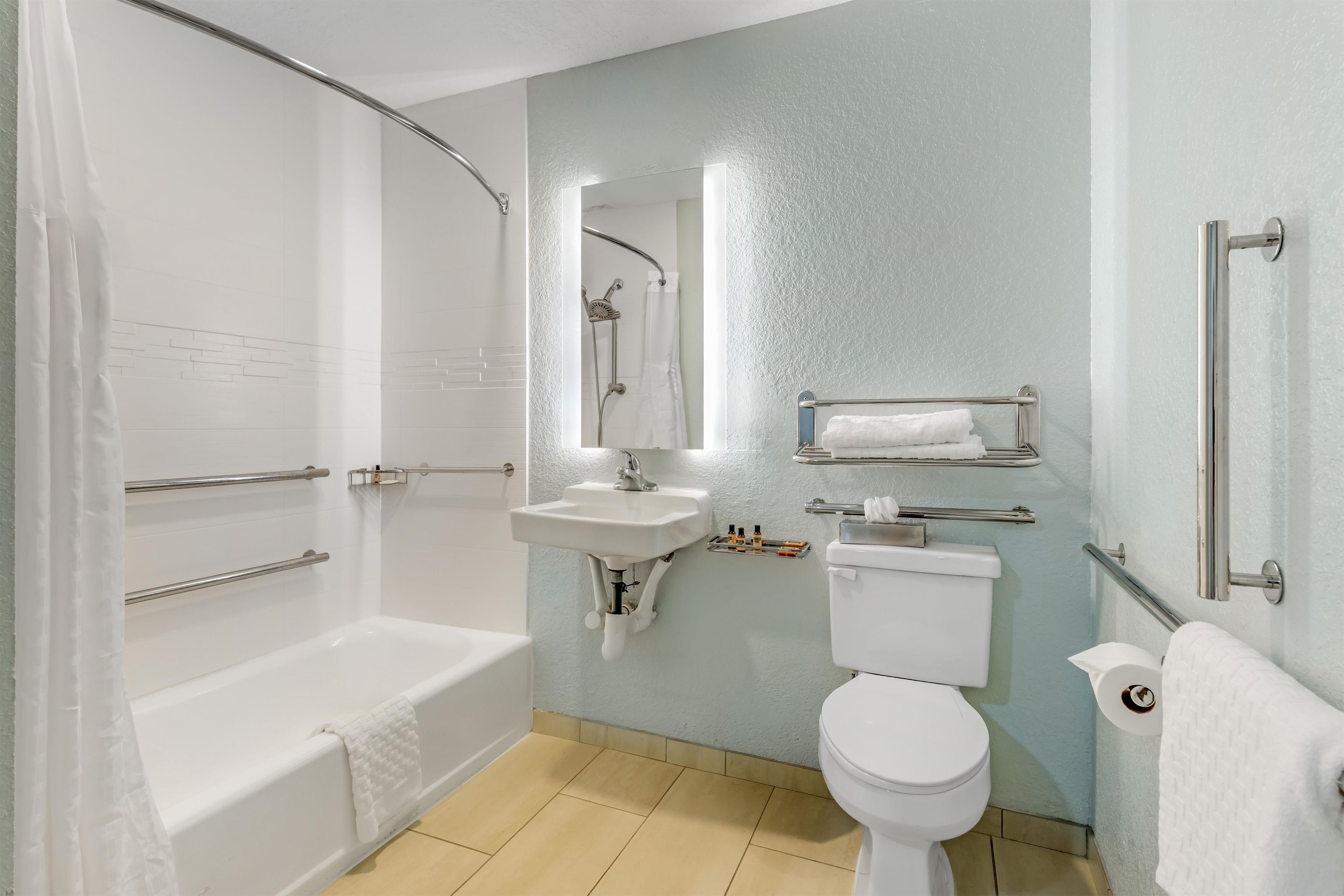 A bathroom with a bathtub, toilet, sink, and a shower area.