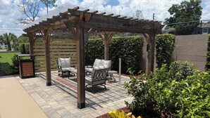 A covered patio area with outdoor furniture and a pergola. - Best Western Plus Orlando East- UCF Area  (Orlando)