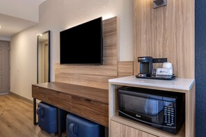 Een moderne kitchenette met een ingebouwde magnetron, koffiezetapparaat en een flatscreen televisie aan de muur.