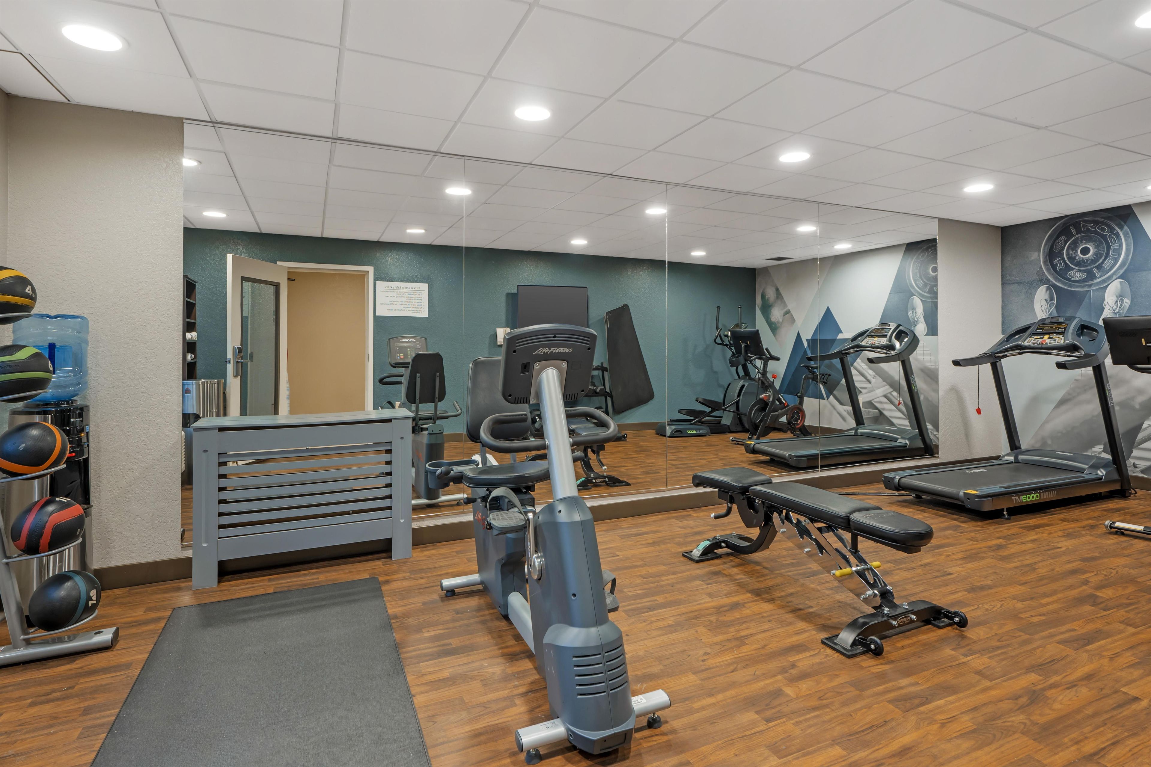 A gym with various exercise equipment, including treadmills, a weight bench, and a rowing machine.