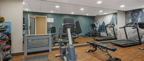 A gym with various exercise equipment, including treadmills, a weight bench, and a rowing machine.