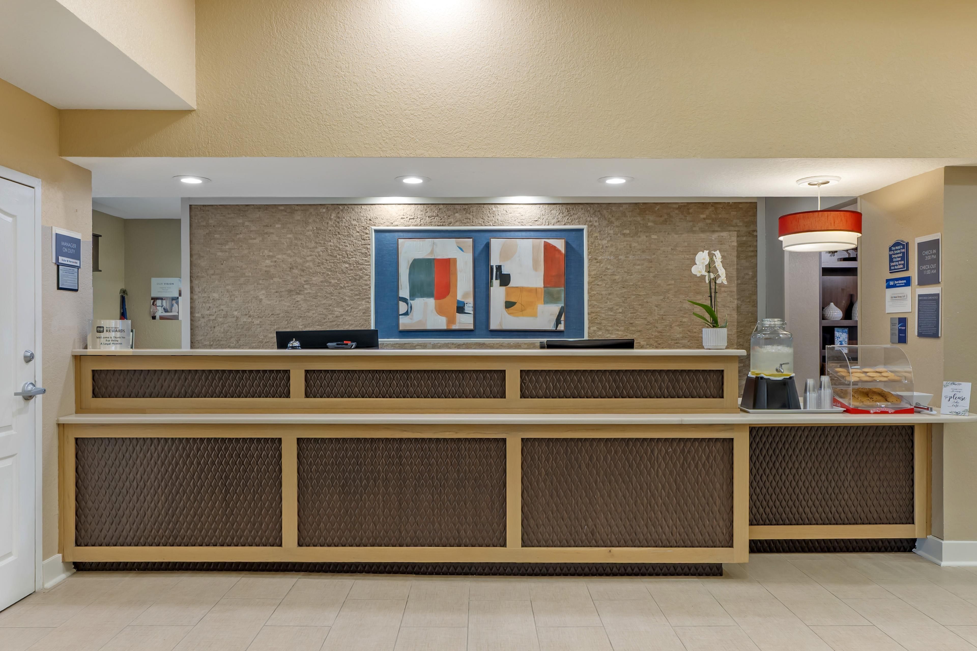A reception desk with a modern design, a check-in counter, and a decorative wall with abstract art.