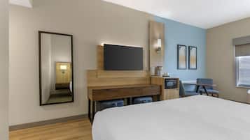 Una camera d'albergo con un letto grande, una scrivania con televisione a schermo piatto, una sedia, un tavolino e un forno a microonde.