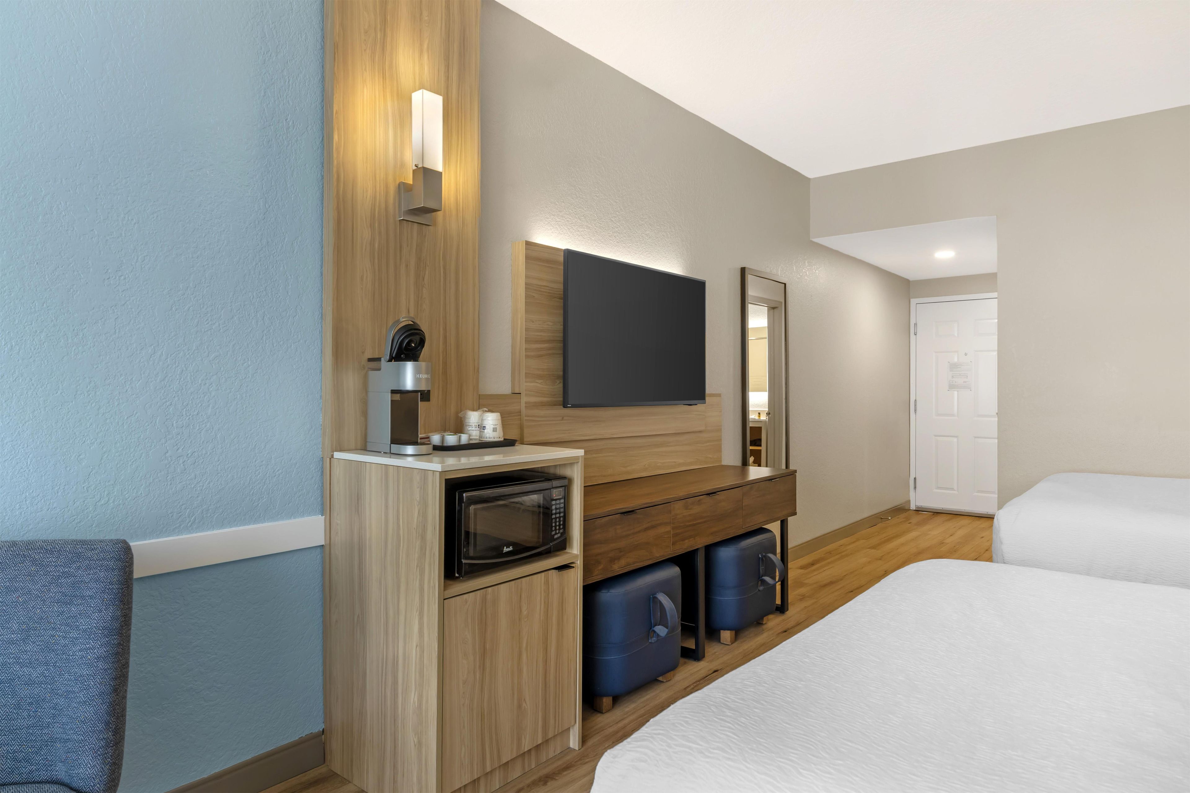 Een hotelkamer met een bed, een bureau met een magnetron, een koffiezetapparaat en een televisie.