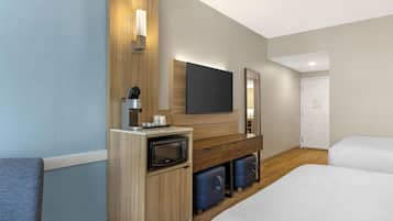 Een hotelkamer met een bed, een bureau met een magnetron, een koffiezetapparaat en een televisie.